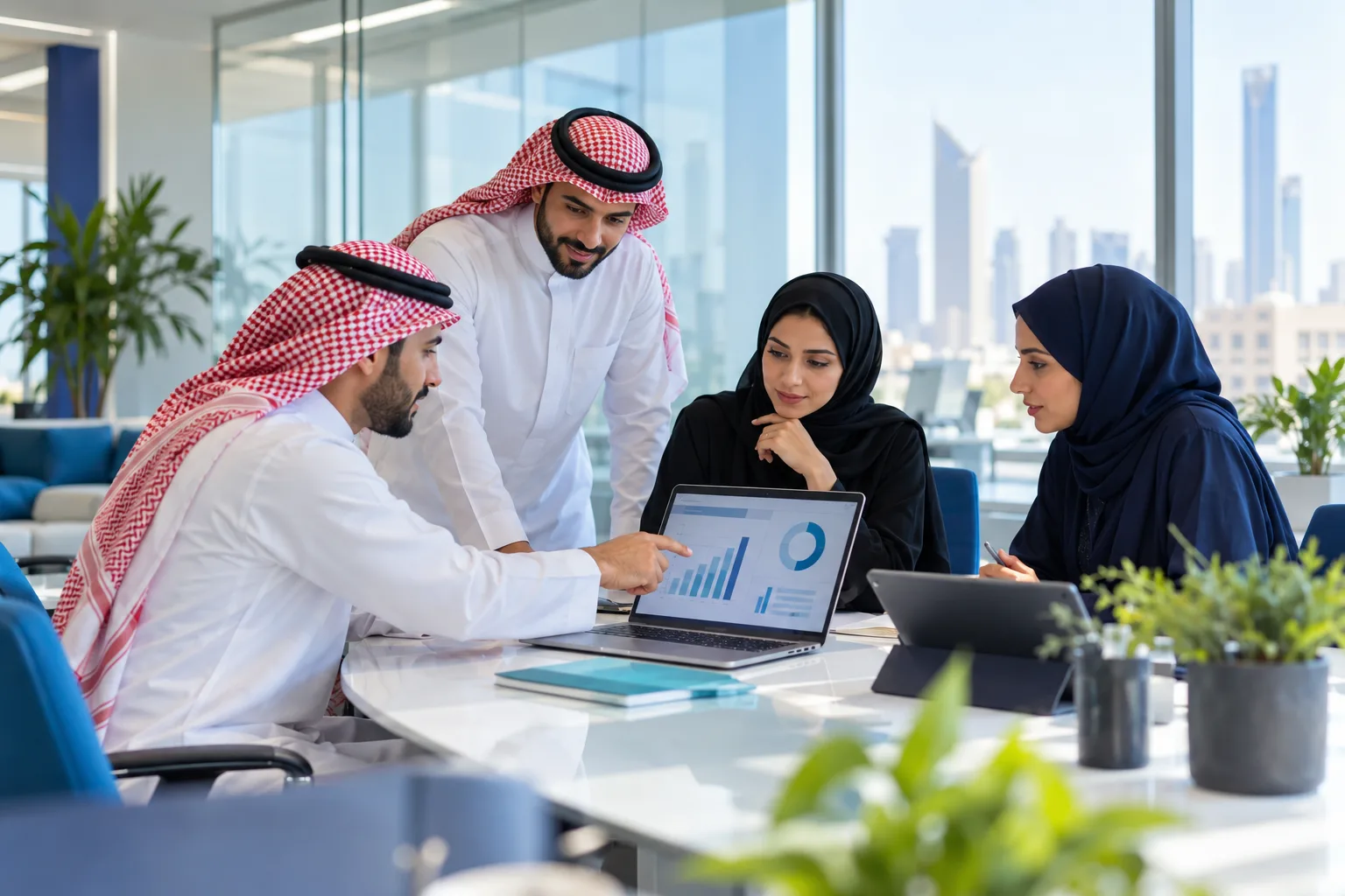 A Saudi team reviewing support performance on a laptop in a meeting room