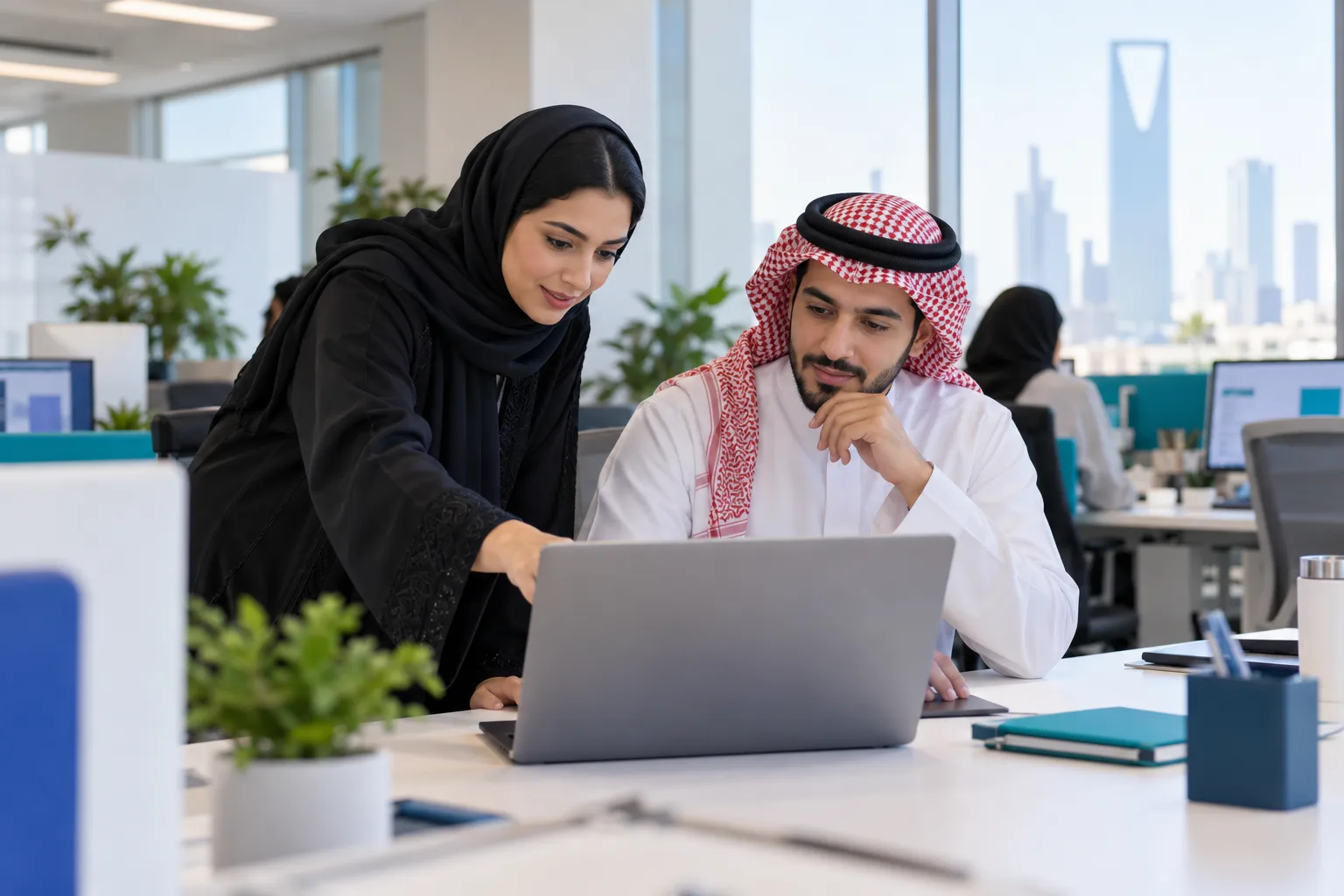 زميلان سعوديان من المبيعات والمحاسبة يختبران مسار إصدار فاتورة على حاسب محمول
