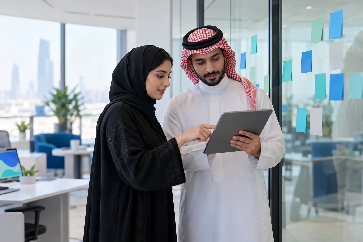 Two colleagues in a Saudi office reviewing ticket categories on a tablet