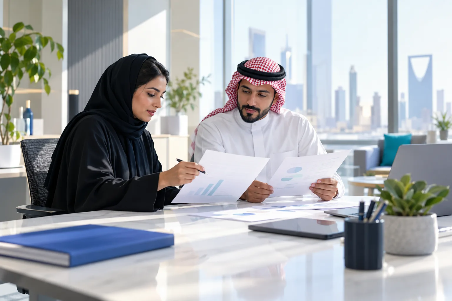 موظفان سعوديان يقارنان عرضي سعر مطبوعين في مكتب مضيء