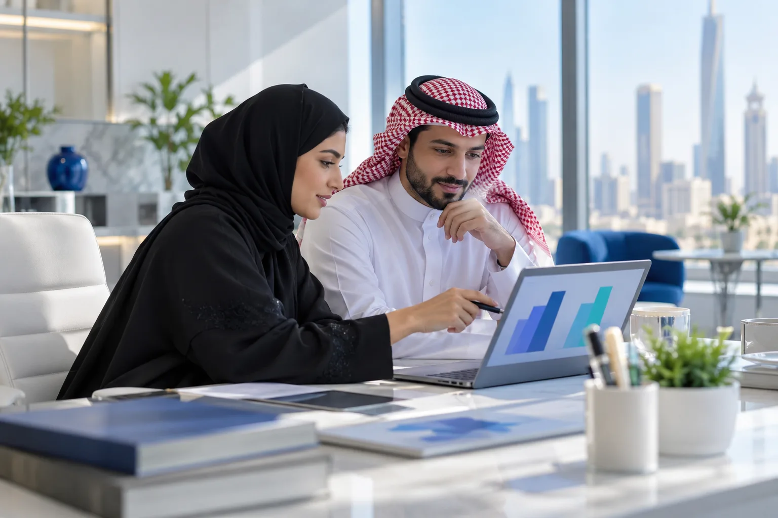 محاسبان في مكتب سعودي يقارنان رقمي إيرادات على حاسب محمول